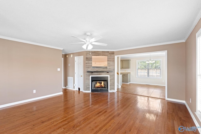 unfurnished living room with visible vents, wood finished floors, a fireplace, crown molding, and baseboards