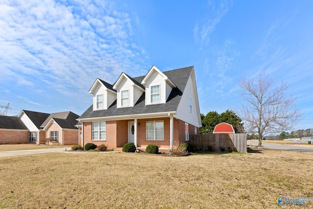 cape cod house with brick siding, a front lawn, and fence