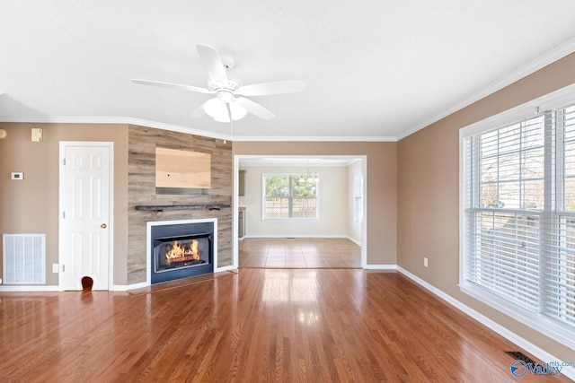 unfurnished living room with visible vents, ornamental molding, a large fireplace, and wood finished floors