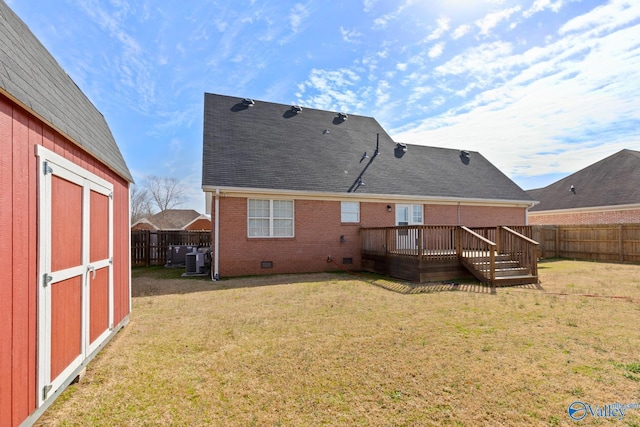 back of property with brick siding, a lawn, a wooden deck, and a fenced backyard