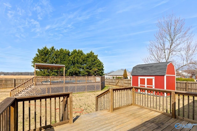 wooden terrace featuring an outbuilding, a storage unit, and a fenced backyard