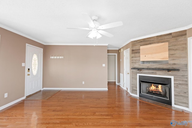 interior space with a fireplace, wood finished floors, baseboards, and ornamental molding