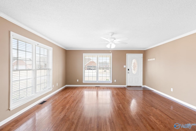 foyer entrance with visible vents, a textured ceiling, crown molding, and wood finished floors