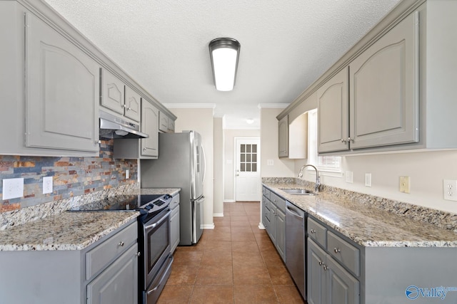 kitchen with a sink, appliances with stainless steel finishes, gray cabinets, and under cabinet range hood