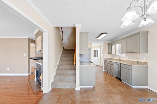 kitchen featuring gray cabinets, a sink, a glass covered fireplace, crown molding, and dishwasher