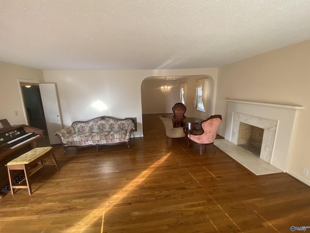 living room featuring a notable chandelier, dark hardwood / wood-style flooring, a high end fireplace, and a textured ceiling