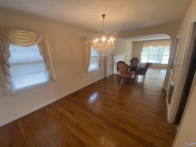 dining area featuring a textured ceiling, dark hardwood / wood-style floors, and a notable chandelier