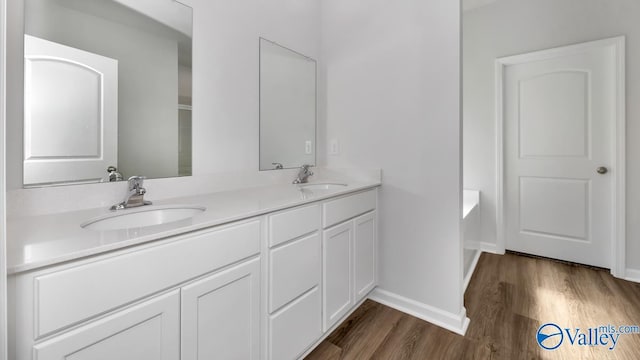 bathroom featuring baseboards, wood finished floors, a sink, and double vanity