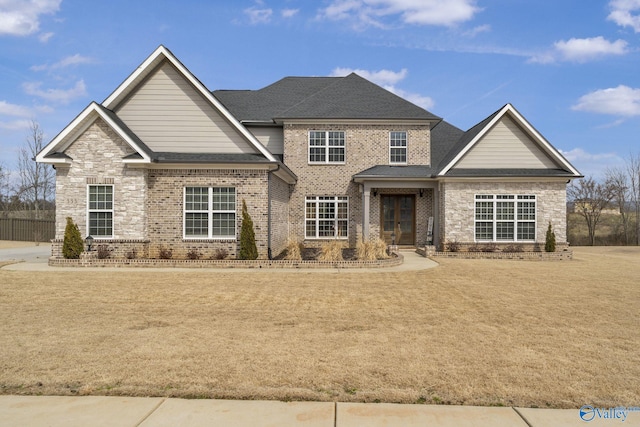 craftsman-style home featuring a front yard, brick siding, and a shingled roof