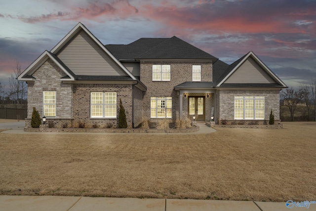 view of front of house featuring french doors, brick siding, a lawn, and a shingled roof