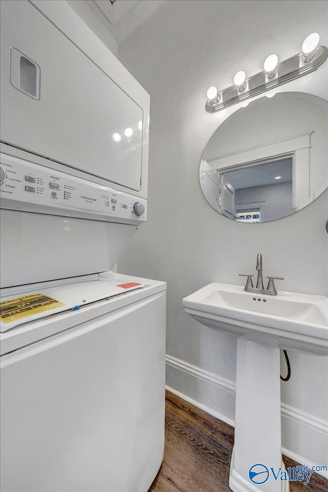 bathroom with sink, wood-type flooring, and stacked washer and clothes dryer