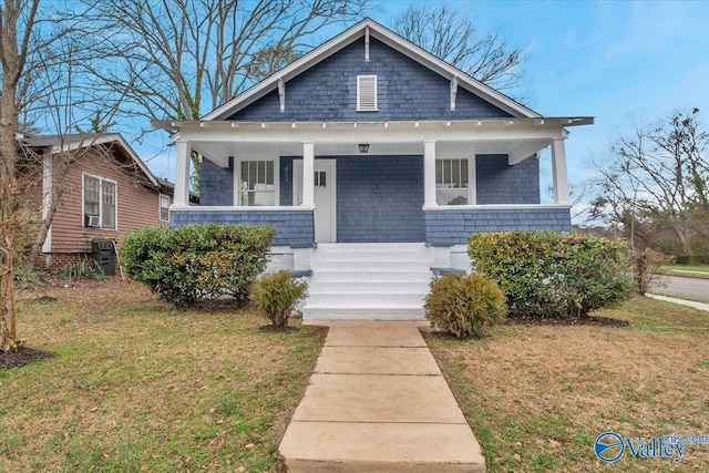 bungalow-style home featuring covered porch and a front lawn