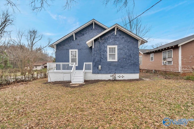 rear view of house featuring a wooden deck and a lawn