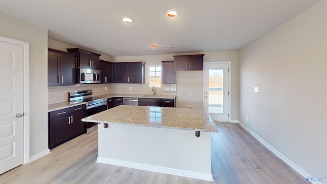 kitchen featuring a center island, sink, decorative backsplash, appliances with stainless steel finishes, and dark brown cabinetry