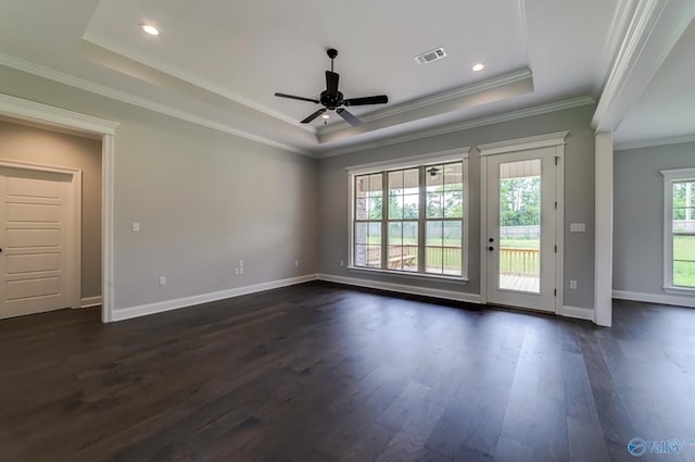 unfurnished room featuring a tray ceiling, dark wood-type flooring, visible vents, and baseboards