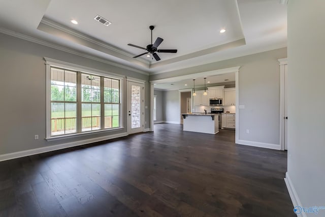 unfurnished living room featuring ornamental molding, a raised ceiling, dark wood finished floors, and baseboards