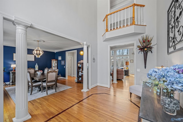 dining area with crown molding, light wood finished floors, baseboards, and ornate columns