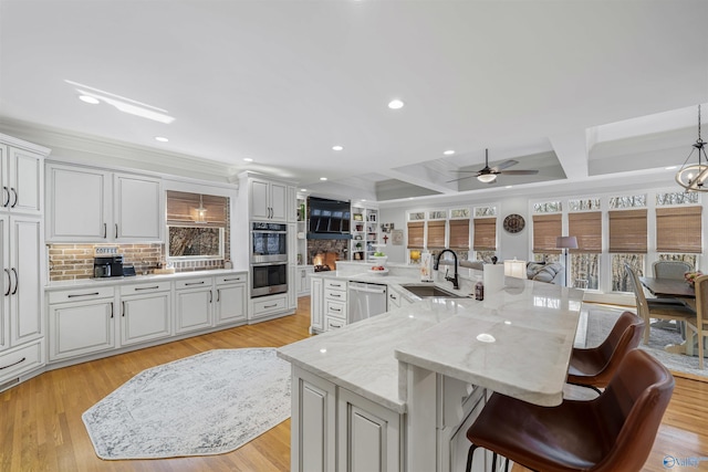 kitchen with a sink, stainless steel appliances, coffered ceiling, and white cabinets