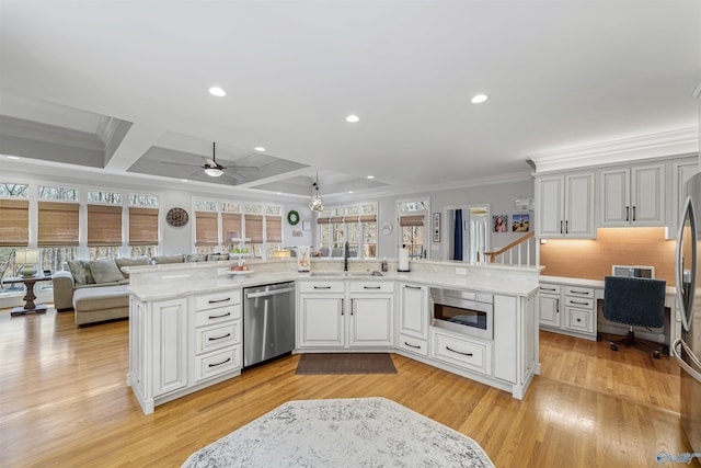 kitchen featuring a sink, open floor plan, built in desk, stainless steel appliances, and crown molding