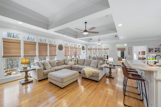 living area with recessed lighting, a raised ceiling, ornamental molding, and light wood finished floors