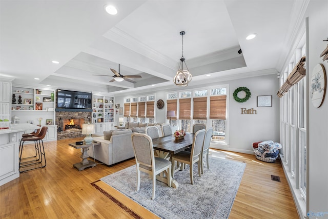 dining room featuring light wood finished floors, visible vents, crown molding, a fireplace, and a raised ceiling