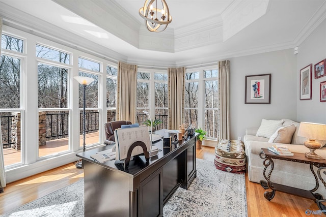 home office with light wood-style flooring, a raised ceiling, an inviting chandelier, and ornamental molding