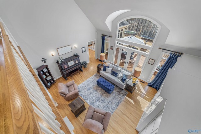 living area featuring baseboards, a towering ceiling, and wood finished floors