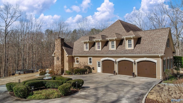 view of front of house featuring stucco siding, driveway, a shingled roof, a garage, and a chimney