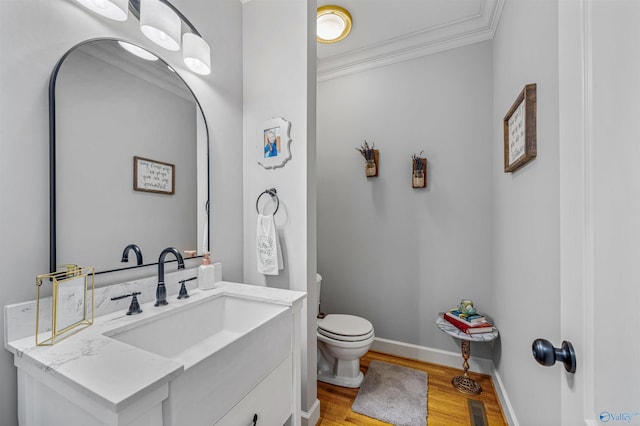 bathroom with wood finished floors, baseboards, visible vents, ornamental molding, and toilet