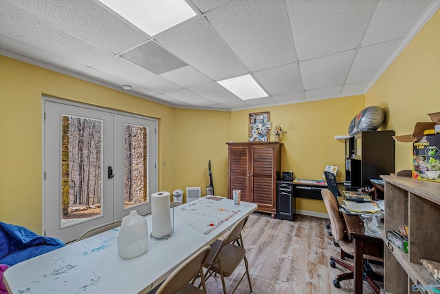 office area with a drop ceiling, french doors, and light wood-style floors