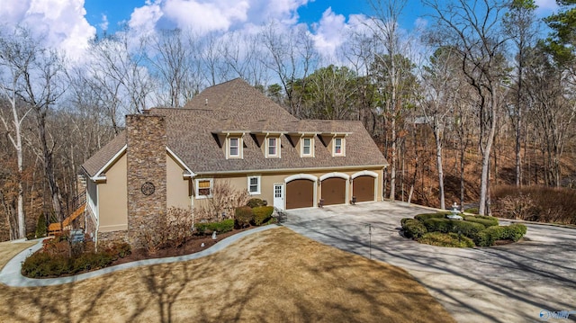 view of front facade with a shingled roof, concrete driveway, a garage, and stucco siding