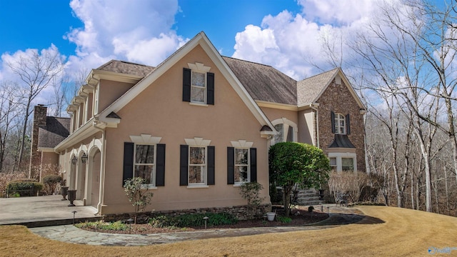 view of side of property featuring stucco siding and a shingled roof