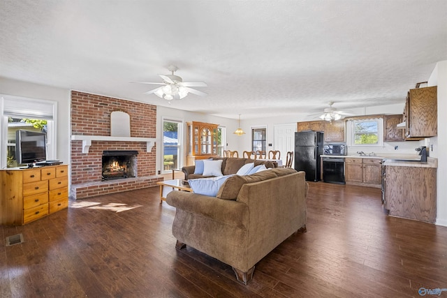 220 County Road 564, Leesburg, AL 35983 - living room featuring a ceiling fan, visible vents, dark wood-style floors, and a brick fireplace