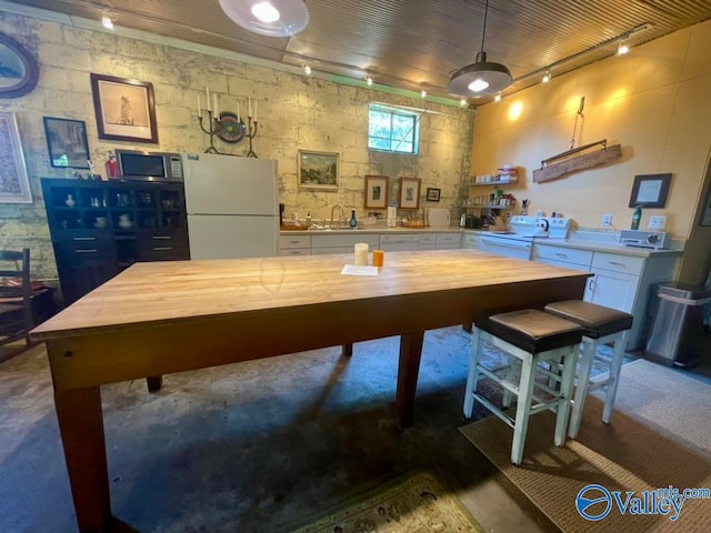 interior space featuring decorative light fixtures, wood counters, sink, white refrigerator, and white cabinets