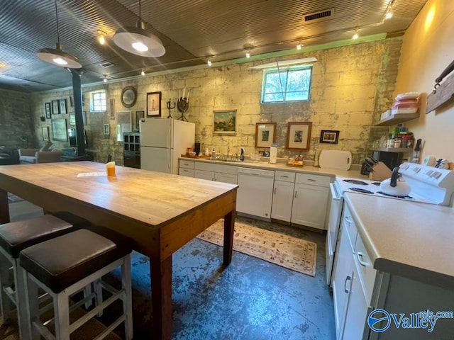 kitchen with concrete floors, white appliances, white cabinetry, sink, and pendant lighting