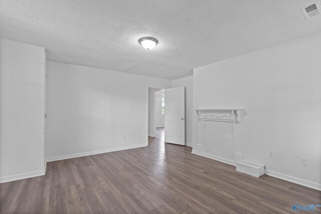 empty room with dark hardwood / wood-style flooring and a textured ceiling