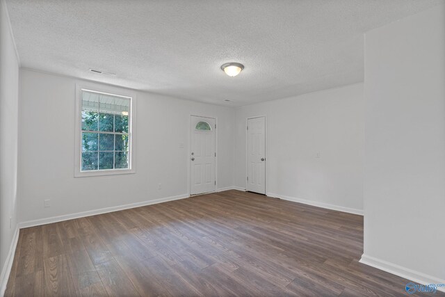 unfurnished room with a textured ceiling and dark wood-type flooring