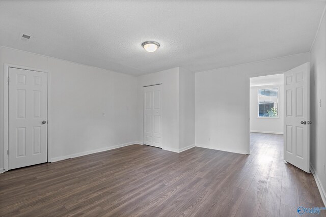 empty room with a textured ceiling and dark hardwood / wood-style floors