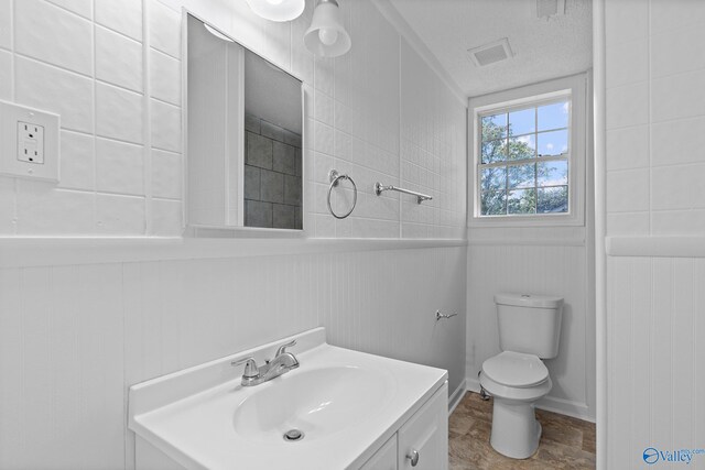 bathroom with a textured ceiling, vanity, and toilet