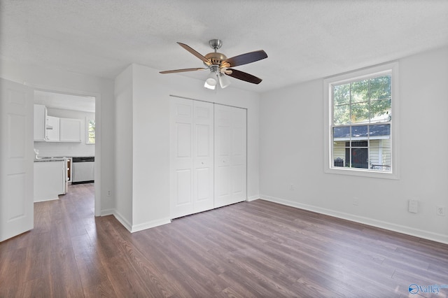 unfurnished bedroom featuring a textured ceiling, ceiling fan, dark hardwood / wood-style floors, and a closet