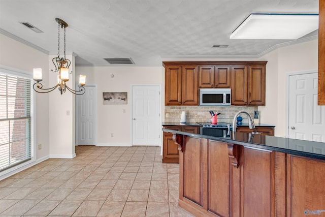 kitchen featuring dark countertops, visible vents, stainless steel microwave, and brown cabinetry