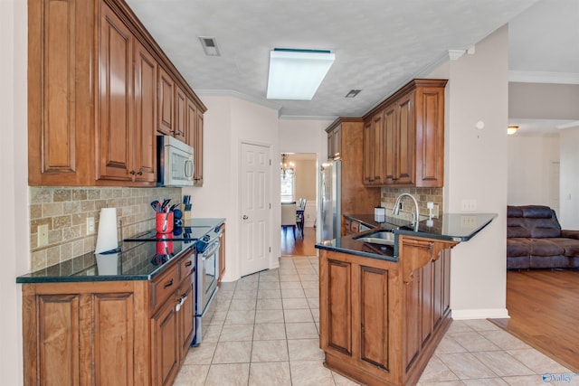 kitchen featuring appliances with stainless steel finishes, a sink, visible vents, and brown cabinets