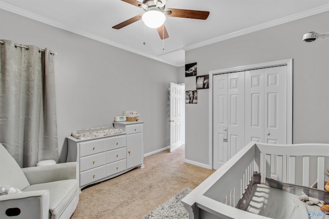 carpeted bedroom featuring ceiling fan, a closet, baseboards, and crown molding