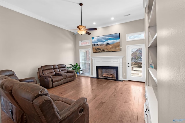 living room with a fireplace with flush hearth, plenty of natural light, light wood-style flooring, and ceiling fan