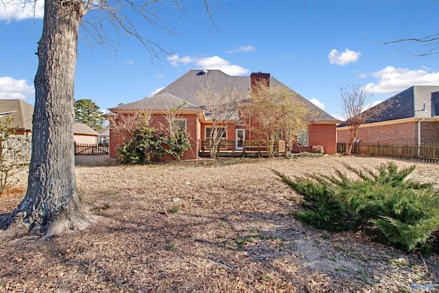 rear view of property featuring a wooden deck, fence, and brick siding