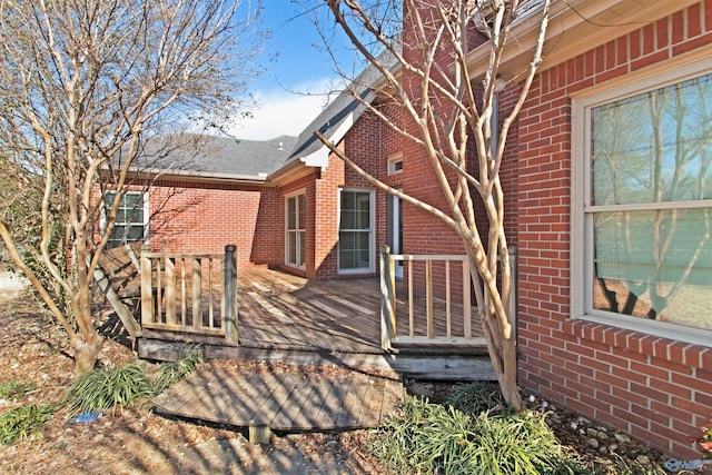 rear view of house with a shingled roof, brick siding, and a deck