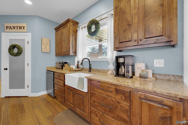 kitchen featuring light stone countertops, dishwasher, light hardwood / wood-style floors, and sink