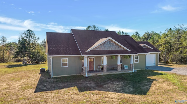 view of front of house featuring a porch, a garage, central air condition unit, and a front yard