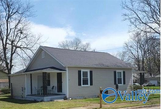 back of property with covered porch and a yard