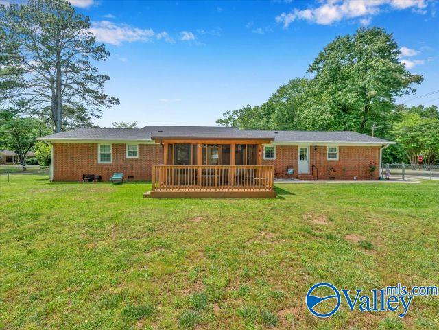 back of property featuring a sunroom, fence, a yard, and brick siding